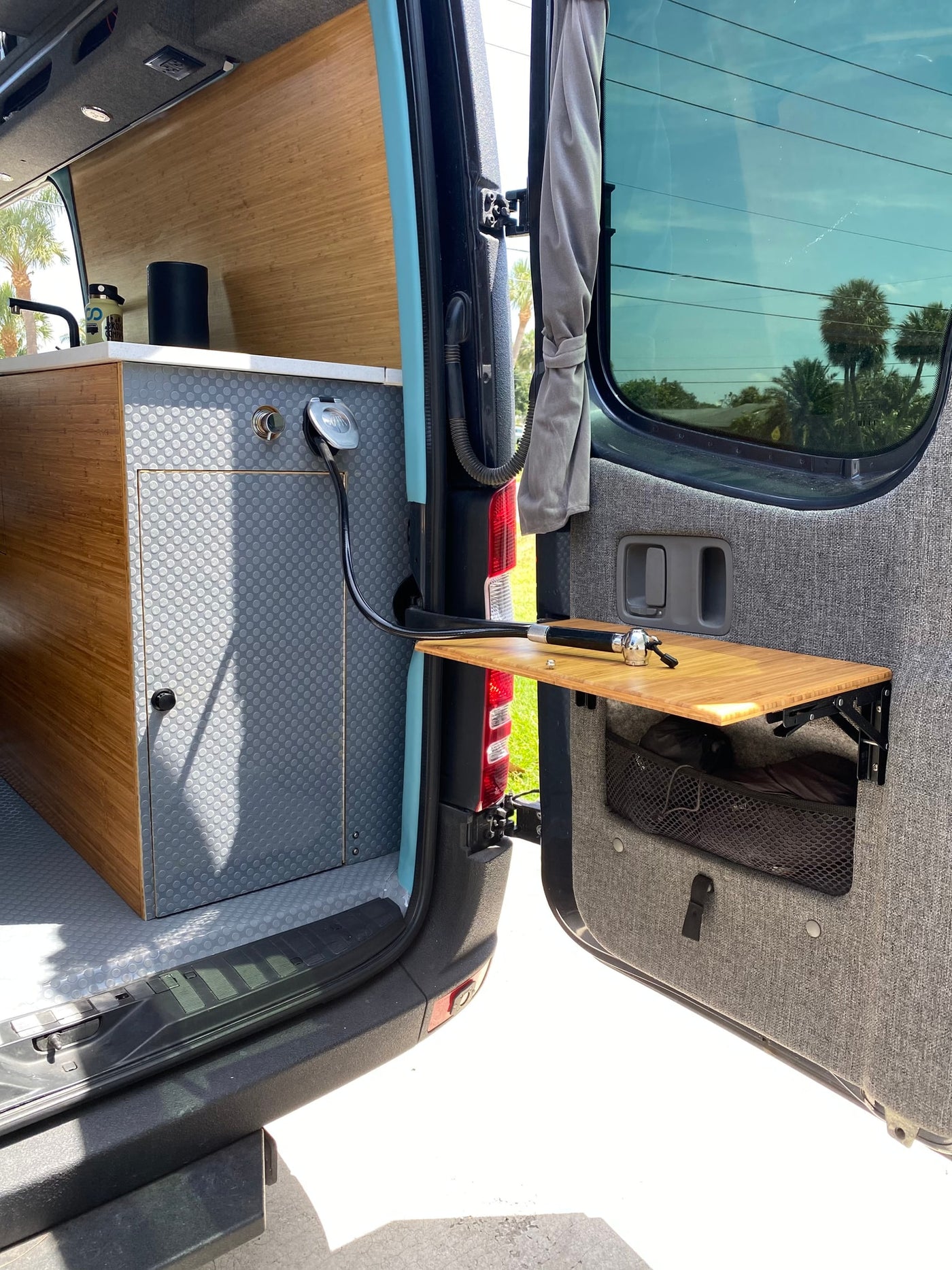 RV rental with functional interior: bamboo kitchen, sink, and outdoor shower setup on rear door table for convenient use. — photo 8