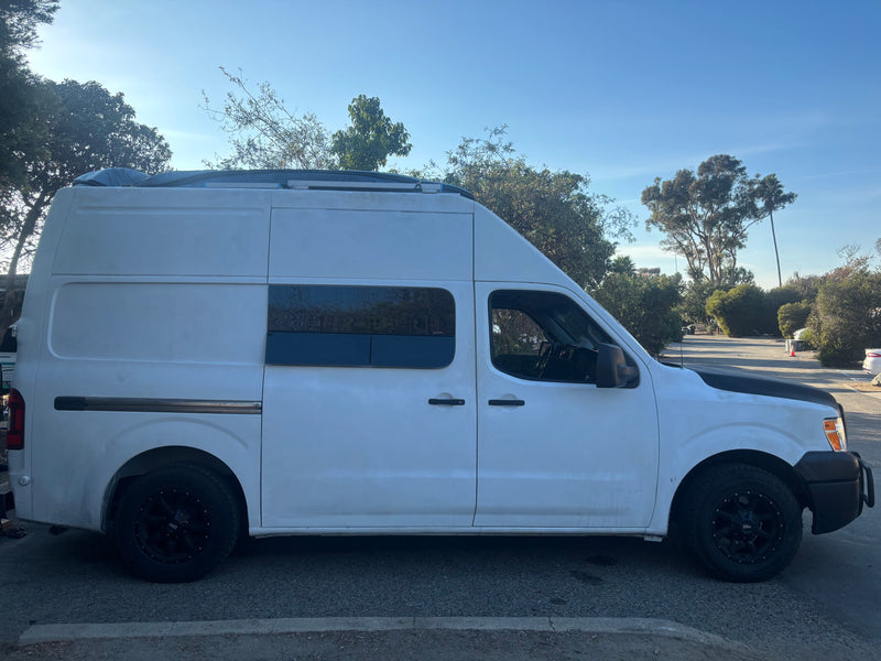 This white high-roof camper van, ideal for an RV rental, features custom windows and roof storage, parked outdoors. — photo 1