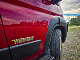 Close-up of a red Winnebago RV, tire, and glossy side reflecting sky and field. Perfect for your next rv rental adventure!