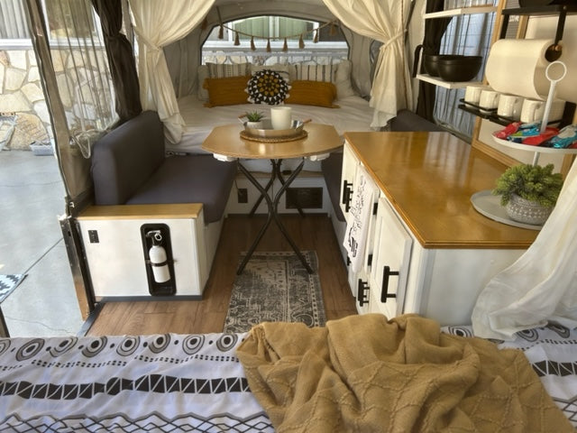 Cozy and functional RV rental interior, showcasing a renovated camper with dining, kitchenette, and comfortable bed.