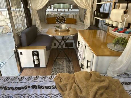 Cozy and functional RV rental interior, showcasing a renovated camper with dining, kitchenette, and comfortable bed.