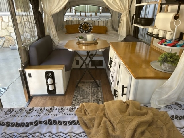 Cozy and functional RV rental interior, showcasing a renovated camper with dining, kitchenette, and comfortable bed. — photo 3