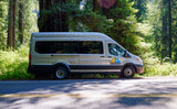 A silver Wandervans RV rental parked on a forest road amidst tall redwood trees, ready for an outdoor adventure.