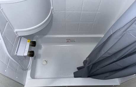 This RV rental offers a compact, clean white shower with visible controls and a practical gray shower curtain.