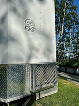 White RV rental trailer from "Look Like a Local" (Palmer, AK) with diamond plate trim, set in sunny Alaska nature.