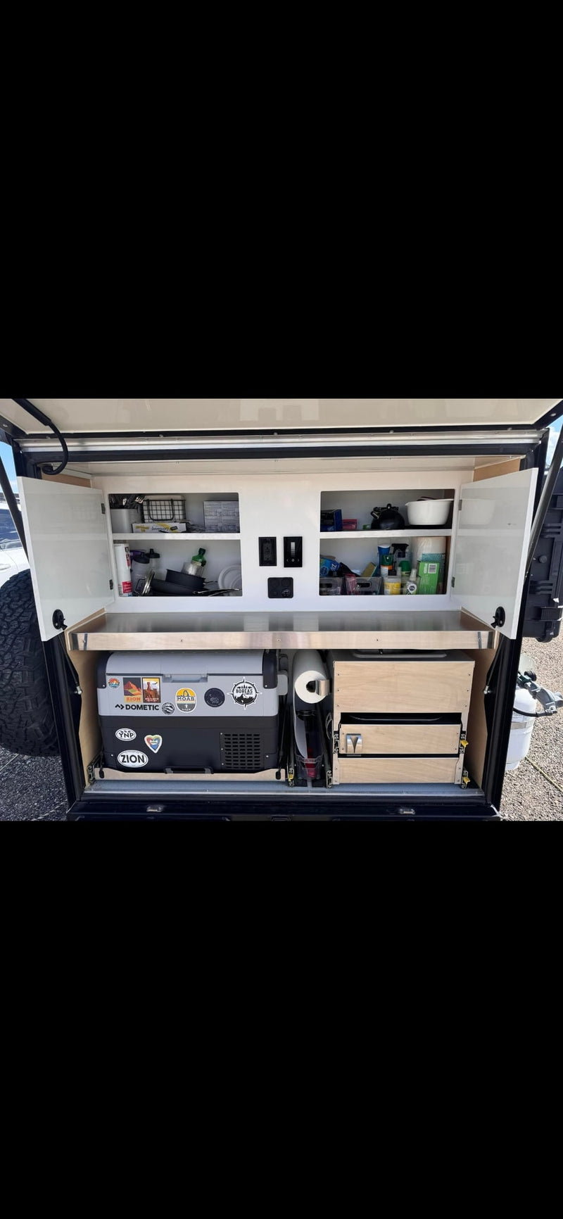 Well-organized rv rental outdoor kitchen featuring a Dometic cooler, slide-out drawers, and stocked cabinets for camping essentials. — photo 8