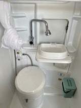 Compact RV rental bathroom with an integrated toilet, small sink, and shower, showcasing efficient design.