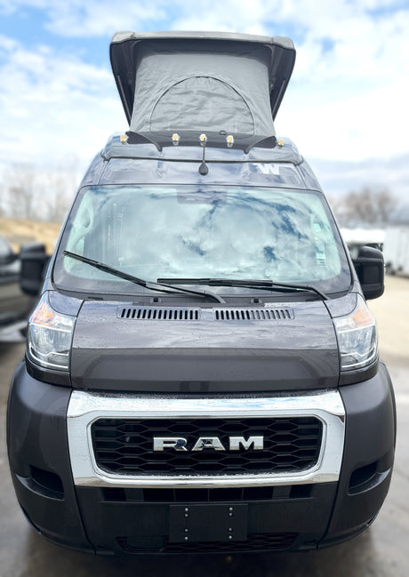 Front view: Rainy dark grey Ram ProMaster camper van with pop-top roof, ready for your next RV rental adventure.