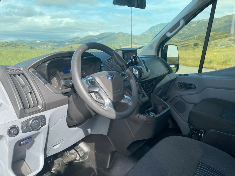 Spacious Ford Transit RV rental van interior with dashboard details, offering a clear view of scenic mountains and fields. — photo 8