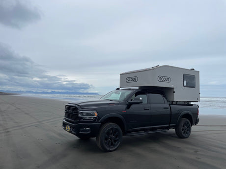 A black Ram truck with a Scout camper