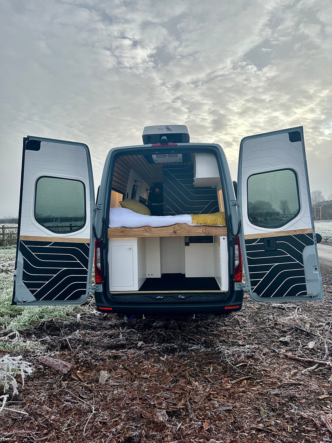 Inside a grey custom campervan. Open rear doors reveal a cozy bed & storage, ideal for an rv rental adventure. — photo 6