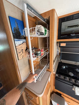 RV rental kitchen: A hand pulls out a multi-tiered pantry rack, optimizing storage for food and supplies.