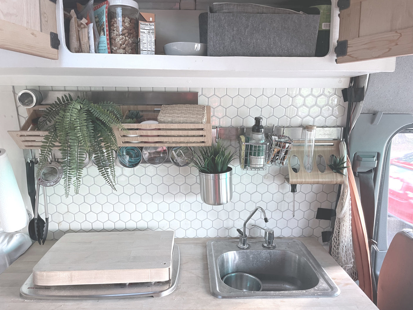 Compact RV rental kitchen featuring a hexagon tile backsplash, sink, and organized wall-mounted storage for a functional cooking space.