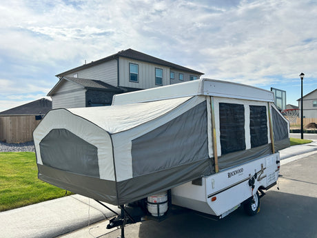 This Rockwood Freedom pop-up camper, perfect for an rv rental, is extended and set up in a residential area.