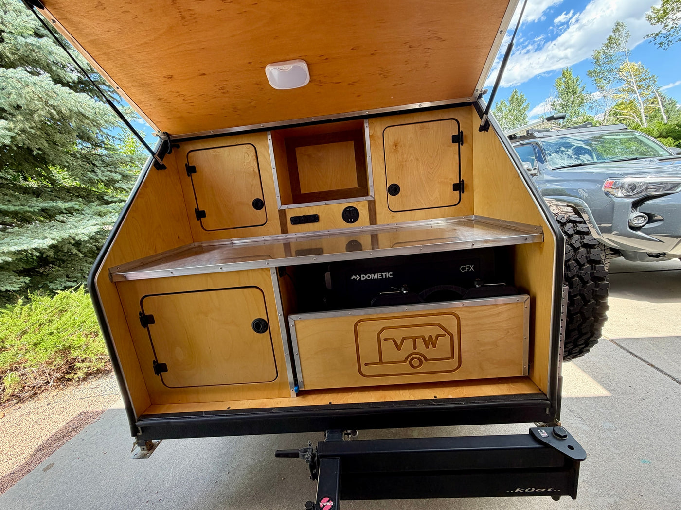 Teardrop RV rental galley showcasing Dometic fridge, power outlets, and custom wooden cabinets. Ready for your next adventure. — photo 6