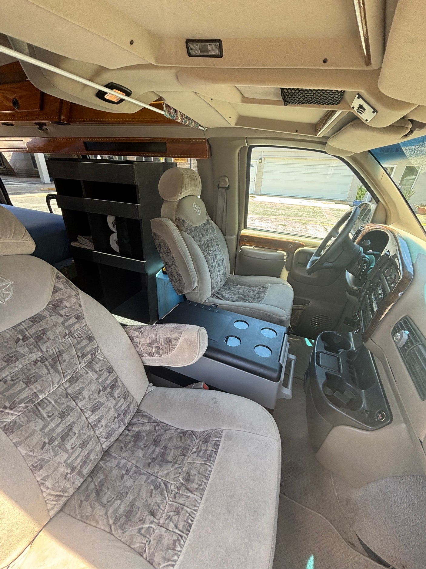 RV rental interior showcasing comfortable front seats, a custom storage unit, and central cooler.