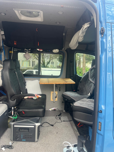 Interior of an rv rental campervan with seating, a folding table, and Anker power for mobile living.
