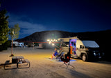 Enjoy a serene night under the stars in your cozy RV rental, complete with string lights, a campfire, and a companion dog.