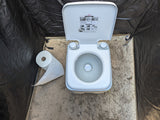 RV rental essential: Portable toilet inside a camping privacy tent, with toilet paper on sand.