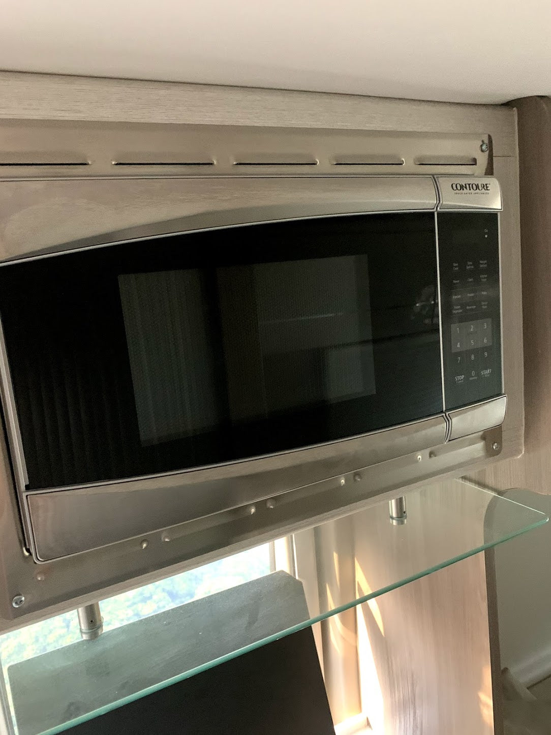 Modern CONTOURE microwave oven, ideal for RV rental adventures. Features an under-mount design with a glass shelf below.