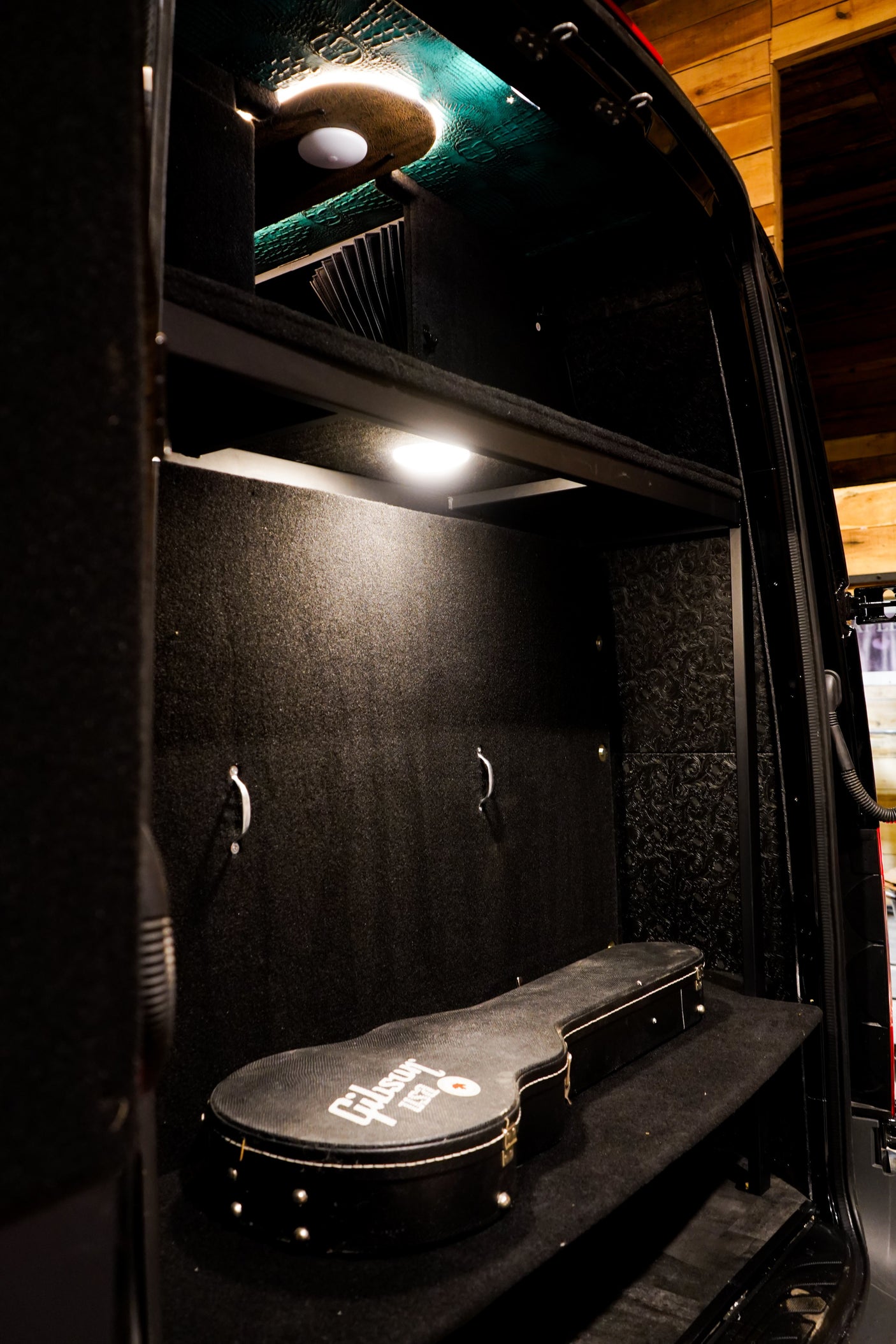 Custom **RV rental** interior with illuminated storage for music gear, featuring a Gibson guitar case.