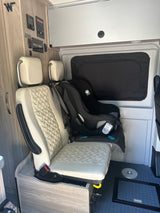 Winnebago RV rental interior: A rear-facing baby car seat is secured in a passenger seat, ready for family adventures.