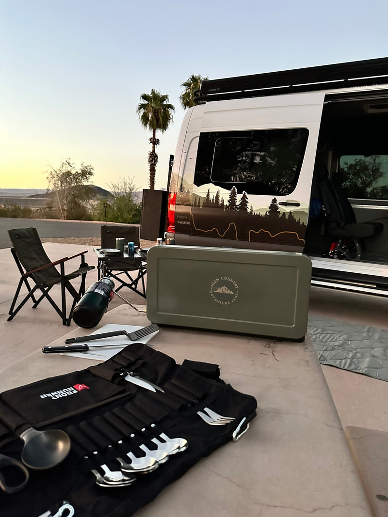 RV rental setup at sunset: A camper van with outdoor kitchen gear, chairs, & cutlery for desert adventures. — photo 7