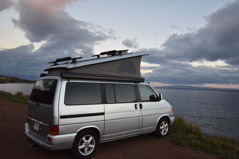 Silver pop-top camper van, an RV rental, parked by the ocean under cloudy skies, with distant land on the horizon. — photo 5
