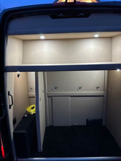 Interior of an RV rental, likely a specialized vehicle like a horse van or trailer, with bright lighting and secure tie-down points.