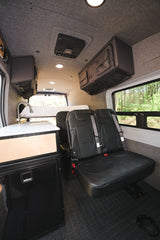 RV rental interior: Kitchen with sink and fridge, two passenger seats, and overhead storage inside a versatile camper van.