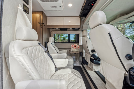 RV rental: luxurious cream leather passenger area with quilted seats, bright interior, and scenic views.
