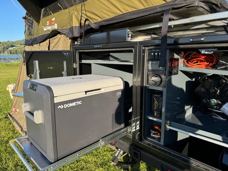 RV rental setup: Dometic fridge on slide-out, 23ZERO rooftop tent, & camp kitchen essentials for outdoor living.