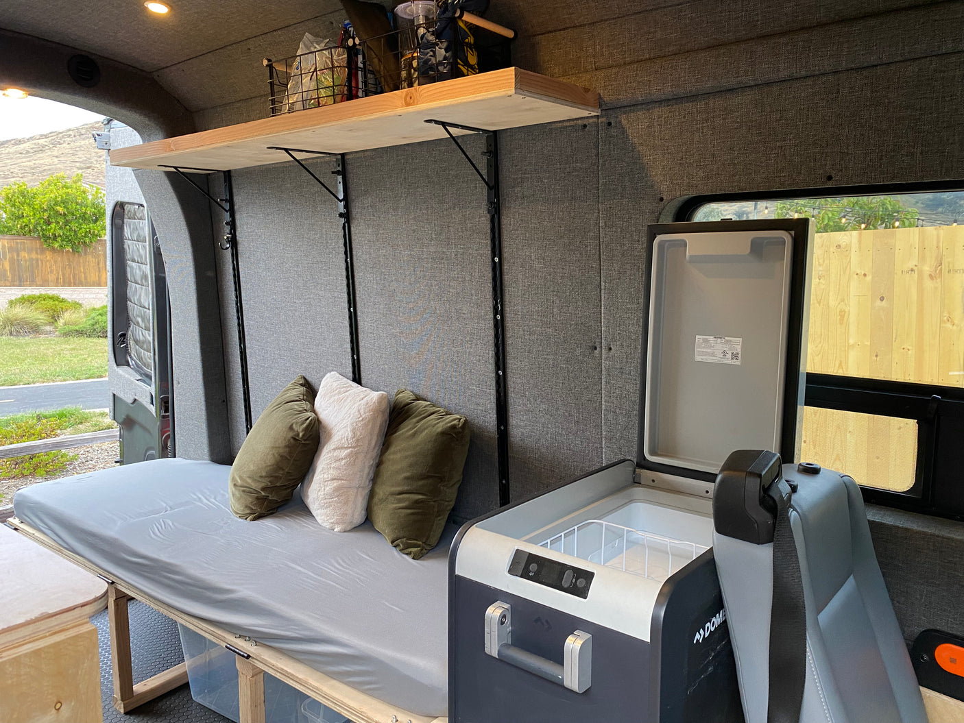 Experience van life in this cozy rv rental. Features a comfy bed, organized overhead storage, and convenient portable fridge.