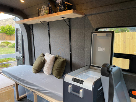 Experience van life in this cozy rv rental. Features a comfy bed, organized overhead storage, and convenient portable fridge.