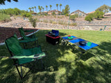 Backyard picnic setup: two green chairs, portable stove, and table on grass. Great for outdoor living after an RV rental adventure.