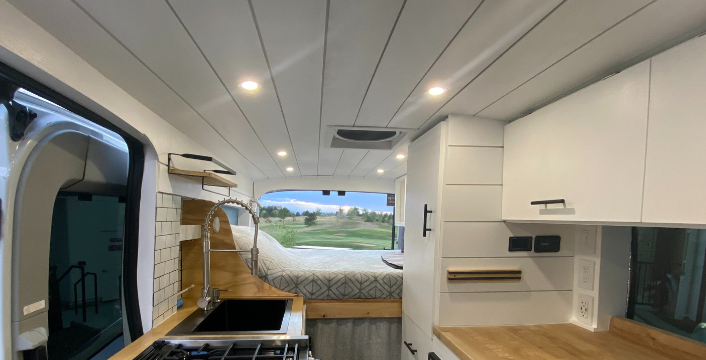 Explore this RV rental: bright interior, complete kitchen with sink/stove, comfortable bed, and panoramic golf course views.