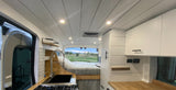 Explore this RV rental: bright interior, complete kitchen with sink/stove, comfortable bed, and panoramic golf course views.