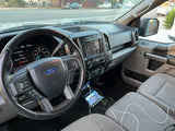 Inside an rv rental: a Ford truck's driver-side interior with dashboard, steering wheel, and infotainment system, set for travel.