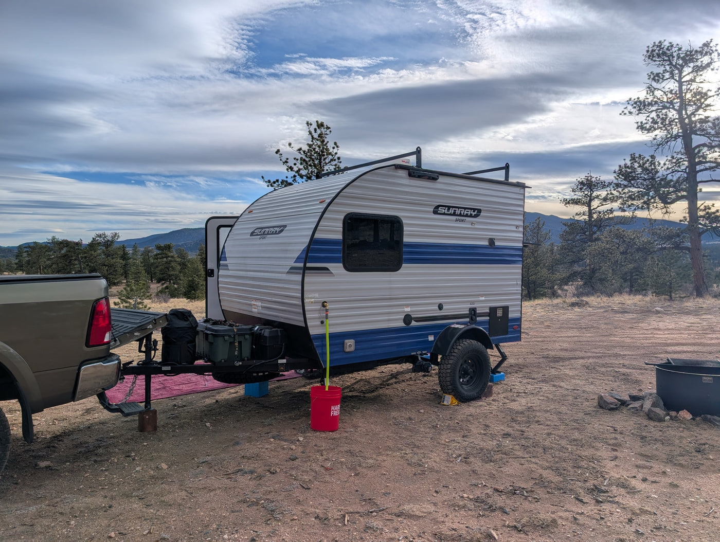 RV rental camping setup: Sunray Sport travel trailer with a truck in a rustic mountain setting under a cloudy sky. — photo 7