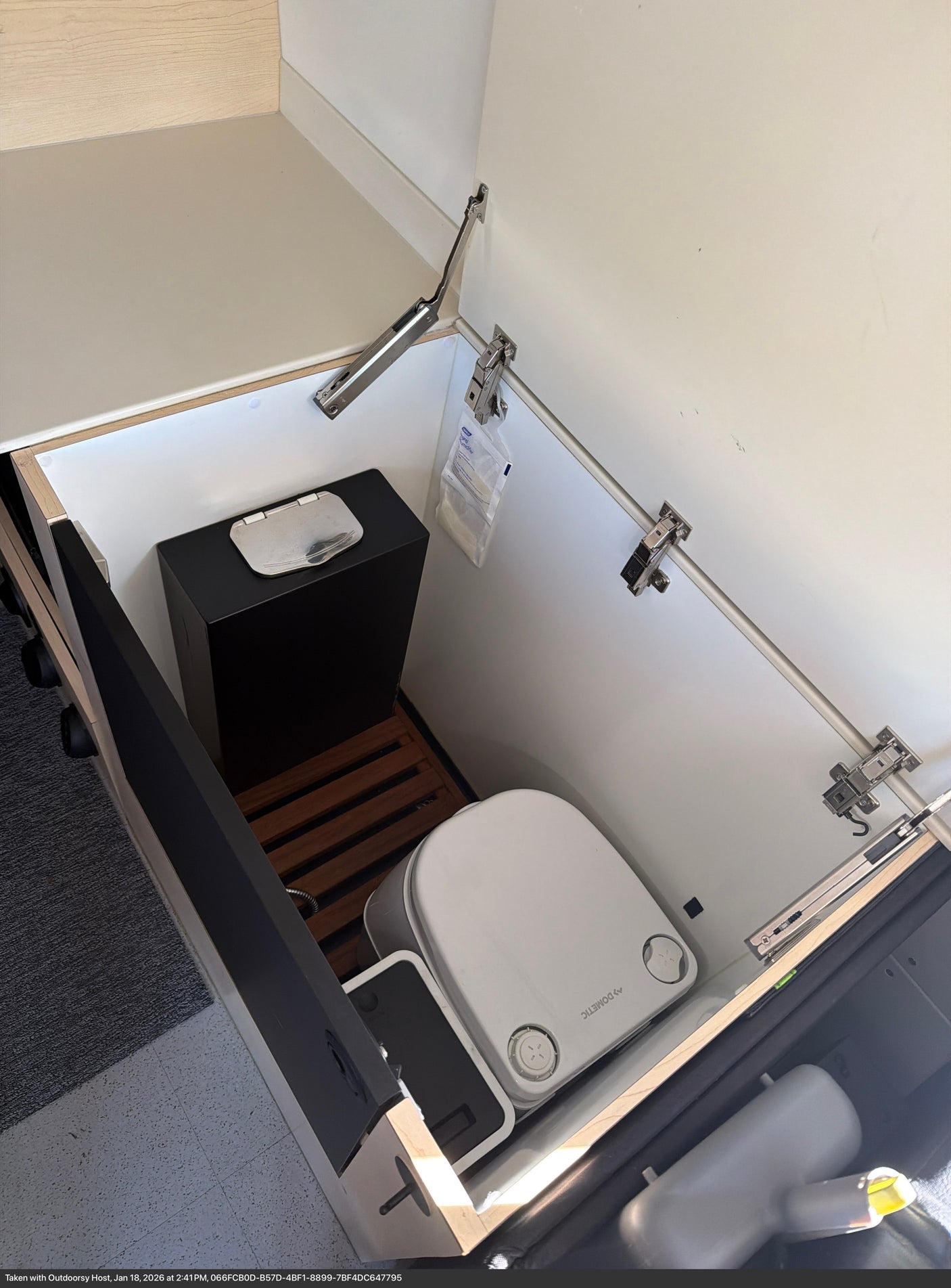 RV rental: Compact hidden compartment with a Dometic portable toilet, waste bin, and essential supplies.