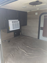 Compact RV rental interior with Frigidaire AC, dark cabinets, and a soft mattress for a cozy stay.