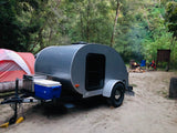 Experience outdoor travel with an RV rental. A small RV, tent, and campfire are ready at a scenic campsite.