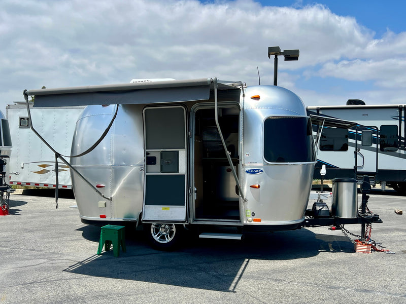 Silver Airstream travel trailer RV rental, with an extended awning and open door, parked outdoors on a sunny day. — photo 5