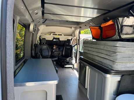 Explore this RV rental's camper van interior: flexible bed setup, ample storage, and front cabin view.