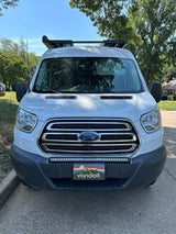White Ford Transit rv rental, full front view. Features a custom 'vandoit' plate, LED light bar, and roof rack for adventure.