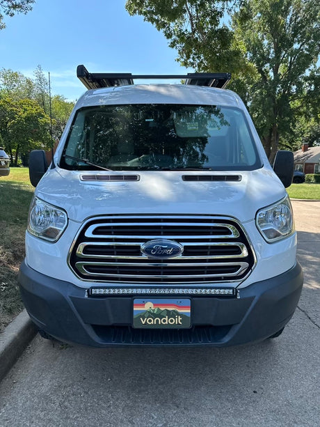 White Ford Transit rv rental, full front view. Features a custom 'vandoit' plate, LED light bar, and roof rack for adventure.