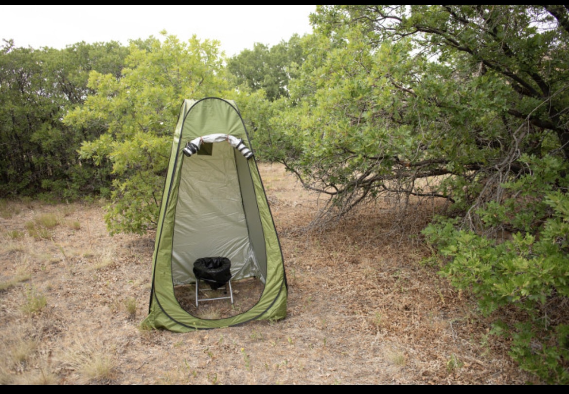 Essential for any RV rental adventure: a portable privacy tent with a camping toilet setup in a natural setting for comfort outdoors. — photo 9