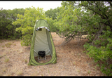 Essential for any RV rental adventure: a portable privacy tent with a camping toilet setup in a natural setting for comfort outdoors.