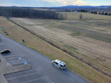 An RV camper van rental parked overlooking historical cannons, a monument, and scenic fields with distant mountains.