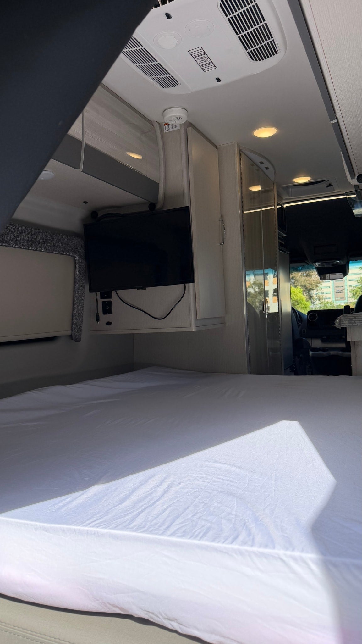  with roof AC and utility access.|Modern rv rental interior: wood-grain overhead cabinets — photo 3